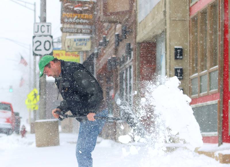 Richie Gall clears snow from the sidewalk along State Street during a snow storm in Marengo on Saturday, November 29, 2025.