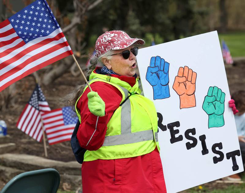 Peg Rozhon, from Malta, sings along with protest and patriotic songs Saturday, May 3, 2025, at Hopkins Park in DeKalb during a May Day Rally for Democracy to protest against Trump administration policies.