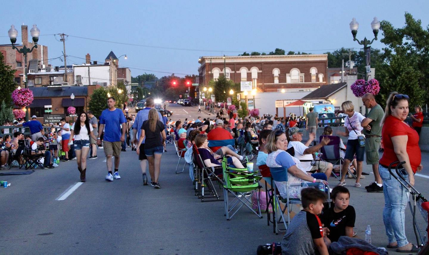 As the sun sets Sunday, people gather on the Peoria Avenue Bridge in Dixon to watch the Petunia Festival fireworks display.