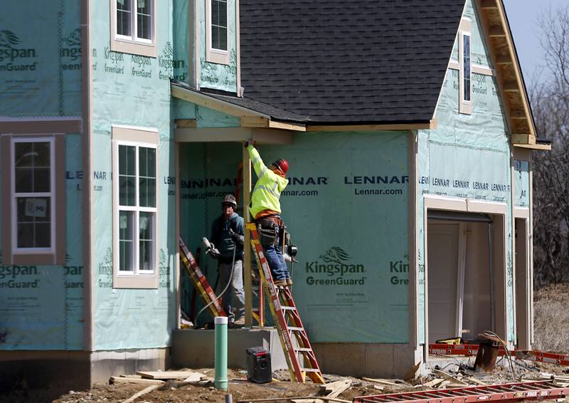 Construction workers work on building a house on Glengary Court Circle Monday, March 28, 2022, in the Woodlore Estates subdivision.