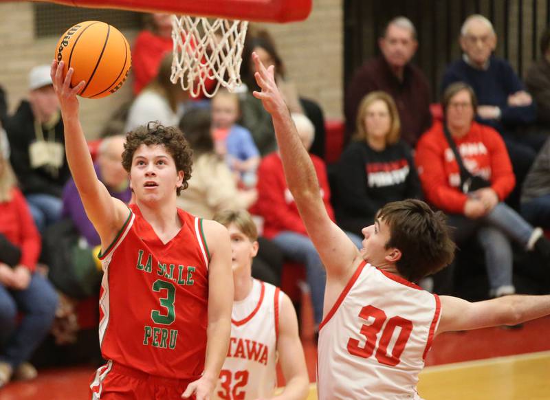 L-P's Mikey Hartman drives to the hoop to score on a layup over Ottawa's Seth Cooper on Friday, Jan. 10, 2024 in Kingman Gym at Ottawa High School.