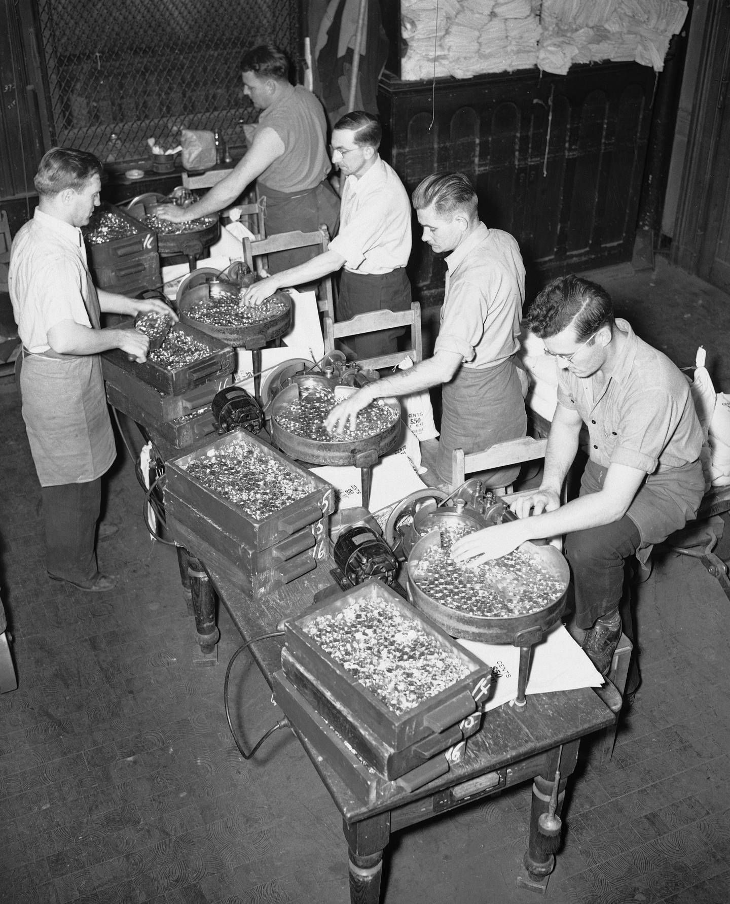 Employees of the U.S. Mint at Philadelphia are working around the clock, seven days a week turning out coins due to the increased demand for copper, nickel and silver pieces throughout the nation, Oct. 30, 1941. Here, workers count and bag copper pieces which become pennies much needed for sales tax payment. The U.S. Mints are making more than 1 billion pennies this year.