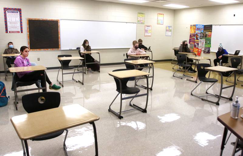 Sycamore Middle School eighth-graders are seated at a safe social distance from each other in January 2021 as they listen to their teacher, Lisa Pawlowski, talk about proper procedures to follow in the classroom to prevent the spread of COVID-19. Sycamore schools resumed some in-person classes today as part of their hybrid learning plan which includes options of in-person and remote learning.