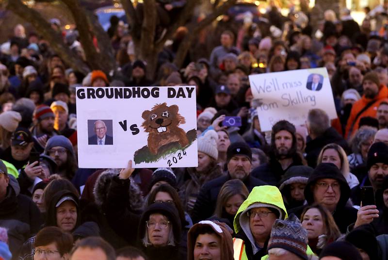 A sign featuring WGN-TV chief meteorologist Tom Skilling and Woodstock Willie is held up on Friday, Feb. 2, 2024, during the annual Groundhog Day Prognostication on the Woodstock Square.