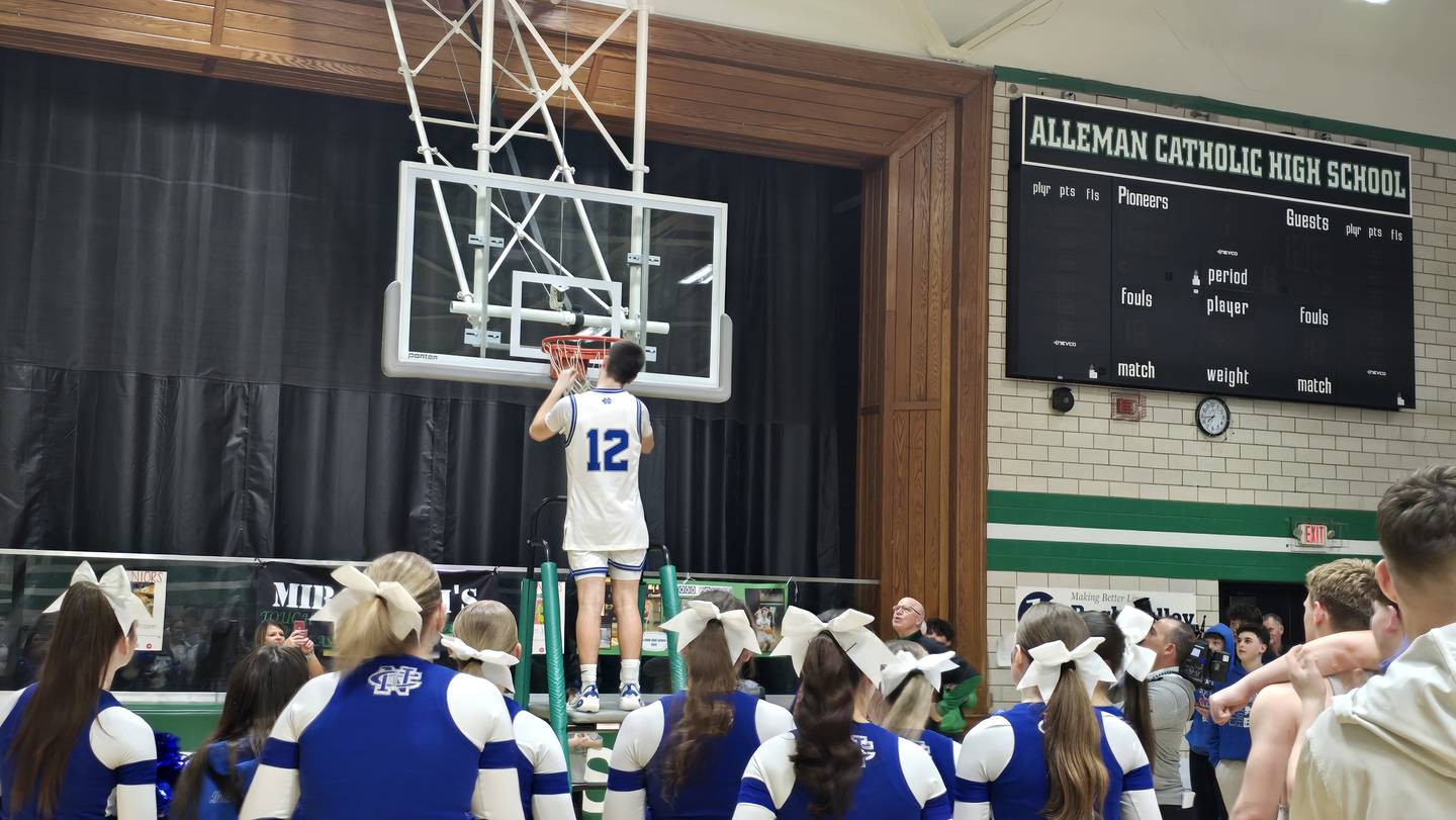 Newman's Evan Bushman cuts down a piece of the net after the Comets won the Class 1A Alleman Regional title on Friday, Feb. 27, 2026.
