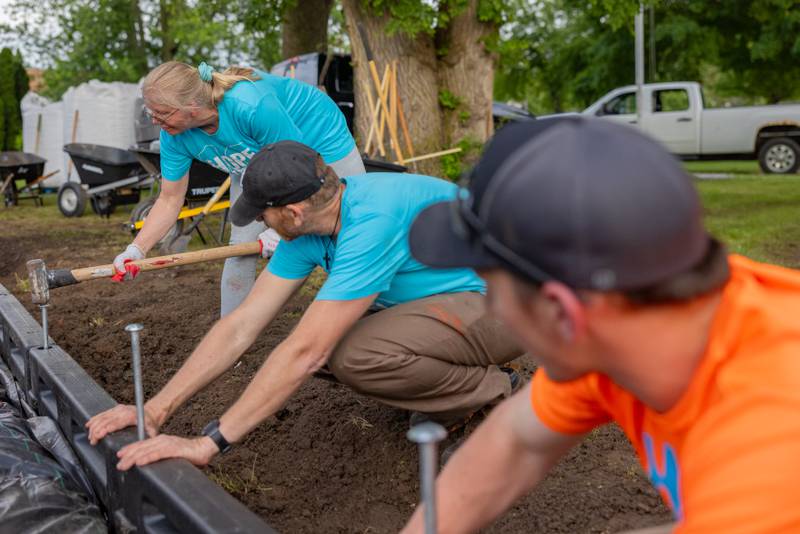 Linda Battaglia drives a stake into landscaping edging to hold rubber mulch for a playground at Grand Ridge Park on June 4, 2025 in Grand Ridge.