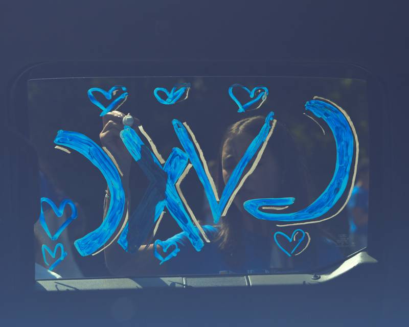 A member of the Geneva girls cross country team decorates the window of the team's float before the start of the Geneva High School Homecoming Parade on Friday, Sept. 26, 2025, along State Street in downtown Geneva.