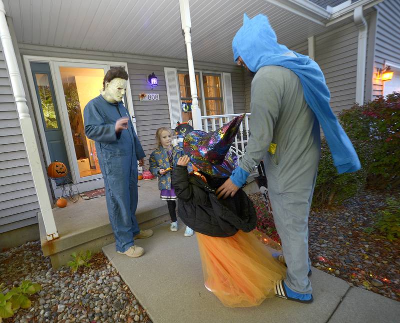 Michael Myers greets a small which and Batman has he hands out treats Friday evening on Ottawa’s South side