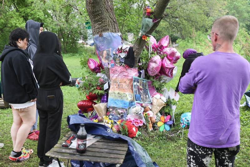 Visitors and friends look at the growing memorial for slain teen Gracie Sasso-Cleveland Friday, May 12, 2023, behind a building in the 500 block of College Avenue in DeKalb.