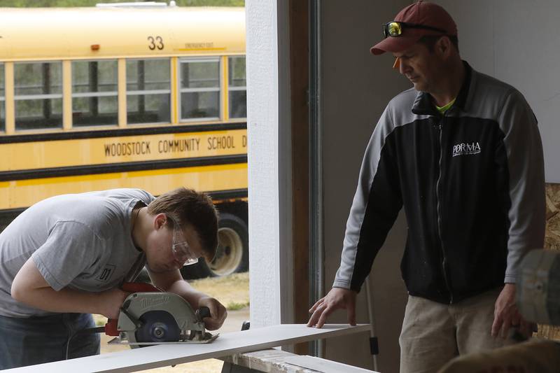 Teacher Erich Parpart watches junior Aaron Hugger make a cut on a stair skirt board as students in the Woodstock Building Trades Program put the finishing touches on a home they are building in Woodstock on Monday, May 8, 2023. This will be the program’s 43rd completed home since the program began in 1972.