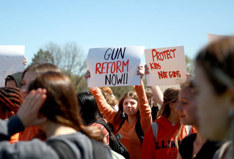 Batavia High School sophomore Emme Stawniak holds up a sign among hundreds of classmates during a walk-out organized by the school’s Students Against Gun Violence club on Friday, April 19, 2024.