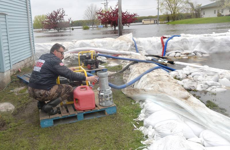 Jacob Helms, a volunteer firefighter with the Savanna Fire Department, refills a gas can on Sunday in preparation of refueling transfer pumps west of Main Street in the city's downtown. Firefighters along with volunteers and inmates from Kewanee and East Moline, constructed the wall with 47,000 sand bags in anticipation of river levels rising past the 21-foot mark. The pumps were beung used to pump floodwaters that seeped under the bags.