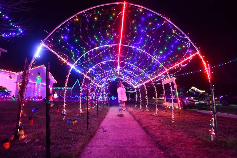 Savannah Phillips, 9, of Key West, Fla., looks up in awe as she and her cousin, Tessa Papineau, 7, of Herscher, walk through a light tunnel on Monday night on North Leiser Street in Herscher. Over a dozen neighbors along the entire street adorn their homes in the glowing decor for the holiday season.