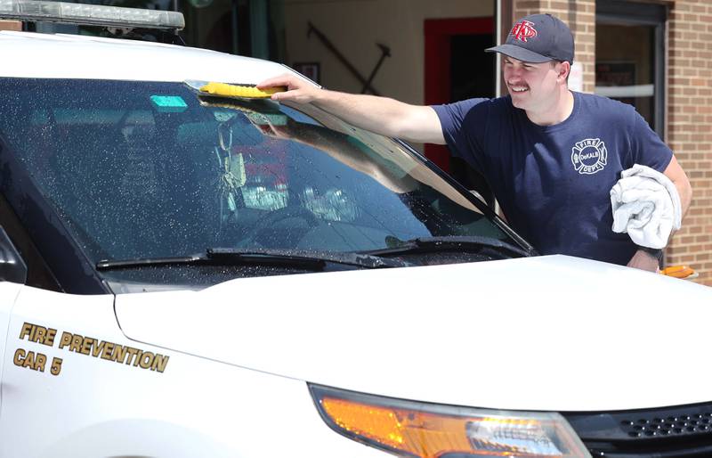 Austin Isham, a firefighter paramedic with the DeKalb Fire Department, washes one of their vehicles Tuesday, May 16, 2023, at Fire Station 1 in DeKalb.