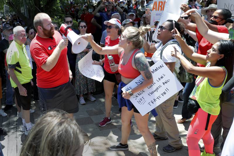 A counter-protester, left in red, is shouted down and has his megaphone taken away by rally attendees for pro-gun control efforts at Discovery Green Park, across the street from the National Rifle Association Annual Meeting at the George R. Brown Convention Center Friday, May 27, 2022, in Houston. (AP Photo/Michael Wyke)