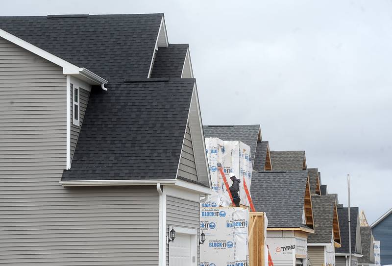 A construction worker builds a home Thursday, April 7, 2022, in the new Trails of Woods Creek, a planned 279-unit subdivision in the Huntley School District.