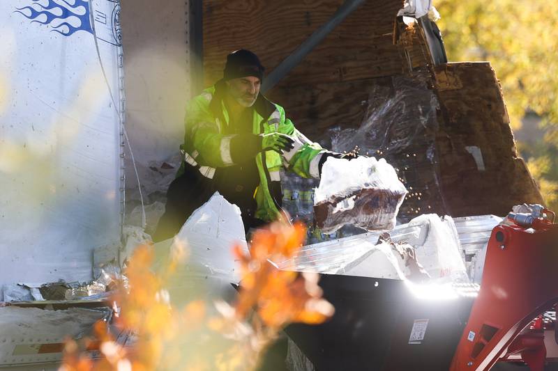 A worker removes damaged soy bean products from a semitrailer. A crash involving two semitrailers shutdown down southbound I-55 as diesel fuel, water bottles and soybeans covered all lanes of Interstate 55 south of the I-80 interchange early Wednesday morning.