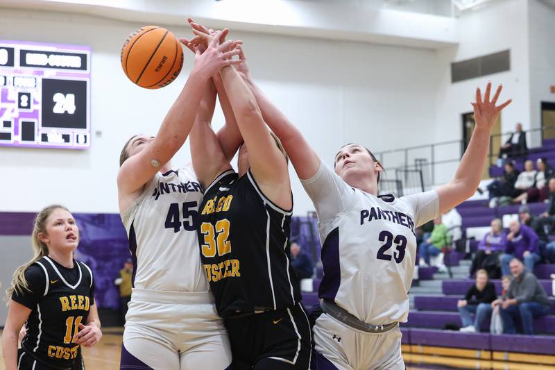 Manteno's Maddie Gesky, right, and Emily Horath, left, reach for a rebound against Reed-Custer's Harlie Liebermann during Reed-Custer's 45-42 victory over Manteno on Monday, Feb. 2, 2026.