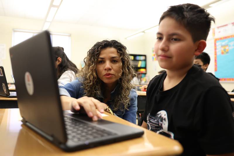 Jenny Cuesta Hernandez, a teacher from Columbia, helps Gael Astorga with his math assignment at Sator Sanchez Elementary in Joliet.