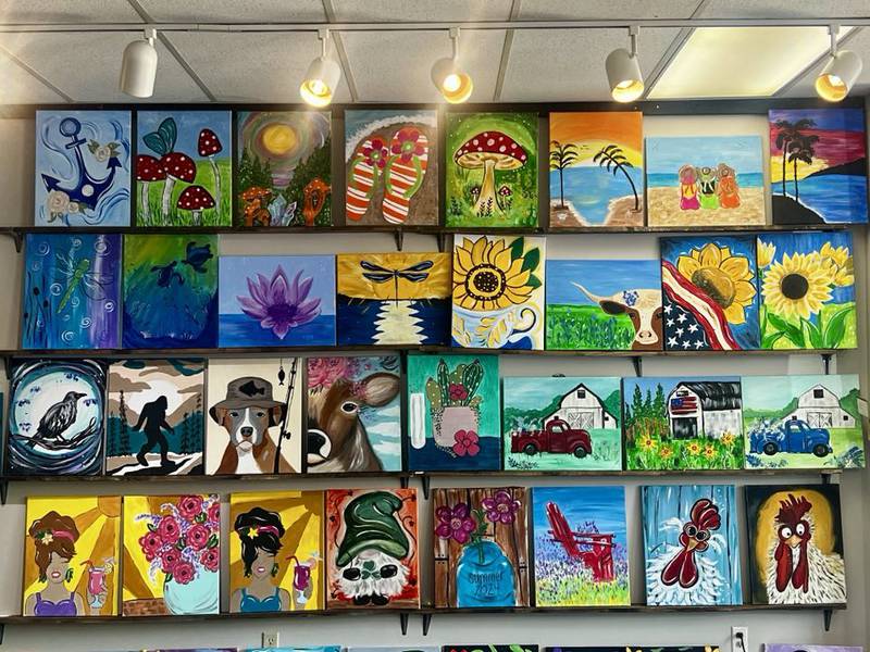 Paintings hang on the wall at the Color Me Happy art studio in Sterling.