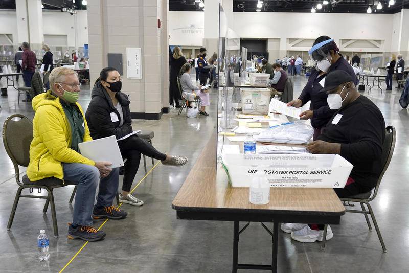 FILE - Election workers, right, verify ballots as recount observers, left, watch during a Milwaukee hand recount of presidential votes at the Wisconsin Center, Friday, Nov. 20, 2020, in Milwaukee. Wisconsin finished a partial recount of its presidential results on Sunday, Nov. 29, 2020 confirming Democrat Joe Biden's victory over President Donald Trump in the key battleground state. Trump vowed to challenge the outcome in court. (AP Photo/Nam Y. Huh)