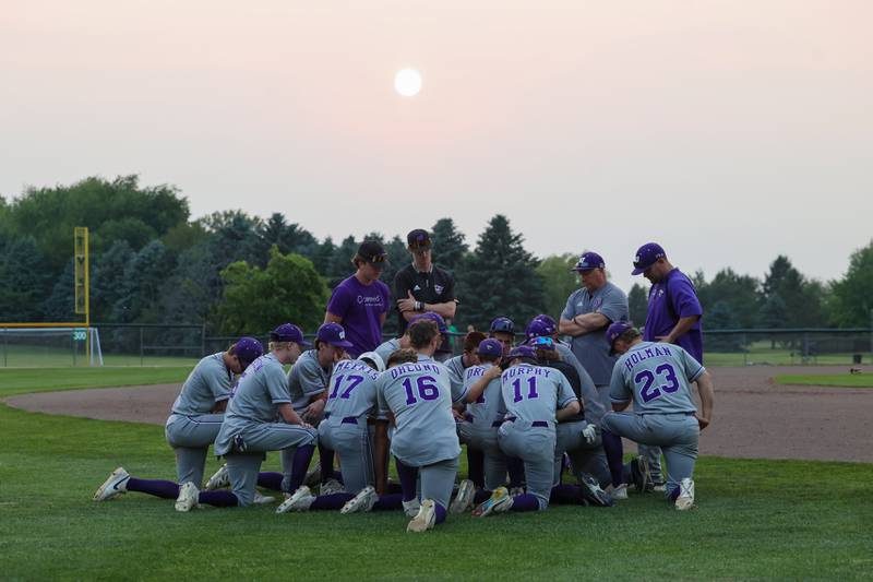 Wilmington players gather in their final huddle of the season as the sun sets following the Wildcats' 4-0 loss to Eureka in the IHSA Class 2A Geneseo Super-Sectional on Monday, June 2, 2025.