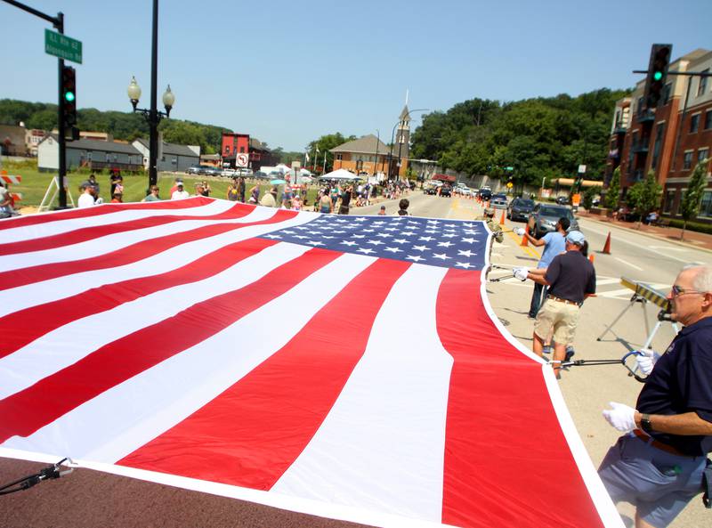 People carry a large flag as part of the Founders’ Days parade along Route 62 in Algonquin Saturday.