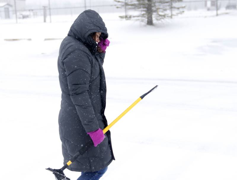 Teacher Leah Pinkowski hangs onto her hood as she walks back to her car after helping another teacher Thursday, Feb. 16, 2023, at Richmond-Burton Community High School in Richmond, after a winter storm moved through McHenry County creating hazardous driving conditions.