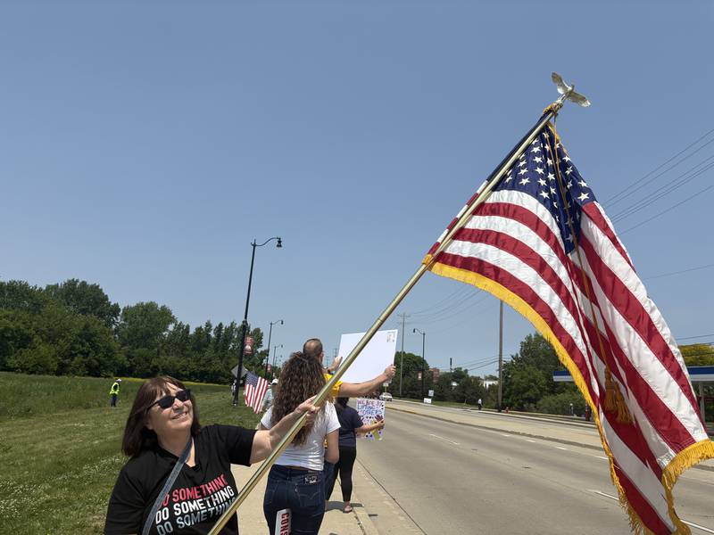 Diane Ayers flys her father's flag during a rally against President Donald Trump in Huntley May 31, 2025.