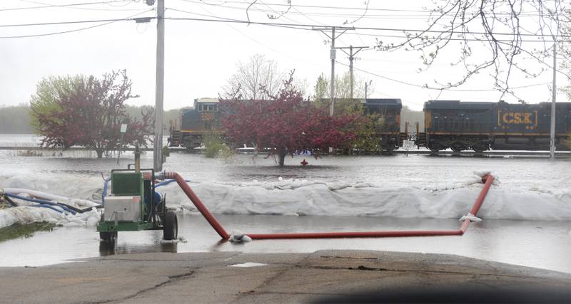 A southbound freight train moves slowly along the elevated railroad tracks just west of Savanna's downtown as Mississippi River floodwaters flow across side streets on Sunday.