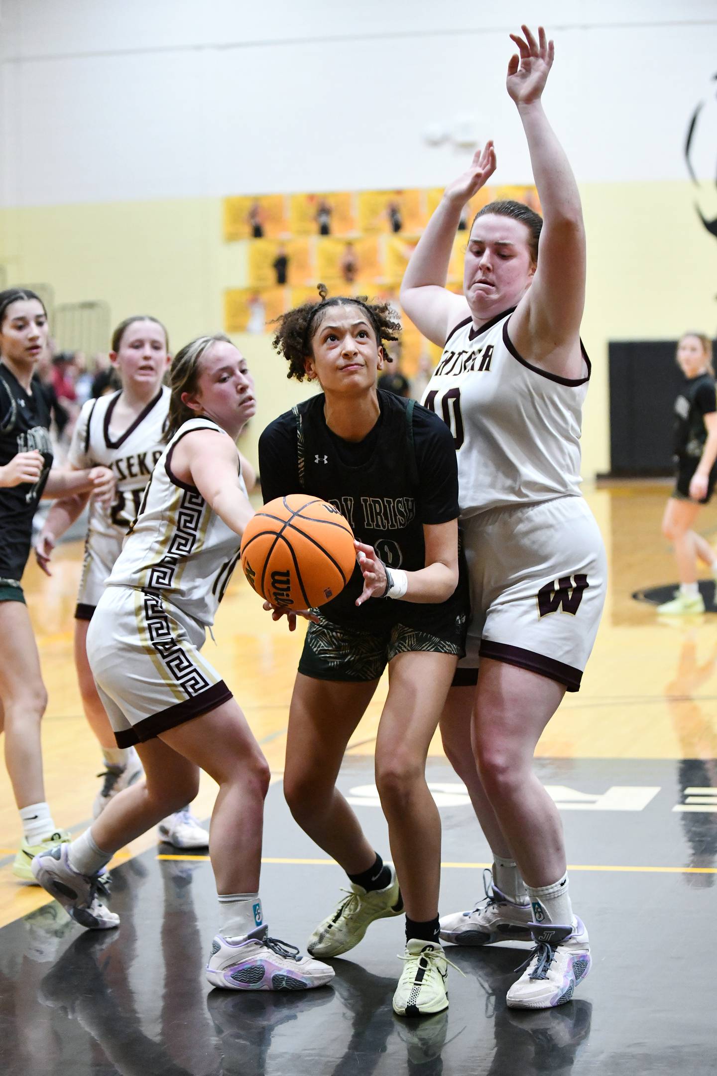 Bishop McNamara's Trinitee Thompson secures an offensive rebound against Watseka-Milford's Megan Martin, right, and Christa Holohan during the Fightin' Irish's 69-38 victory over Watseka-Milford in the IHSA Class 2A Herscher Sectional championship on Thursday, Feb. 27.
