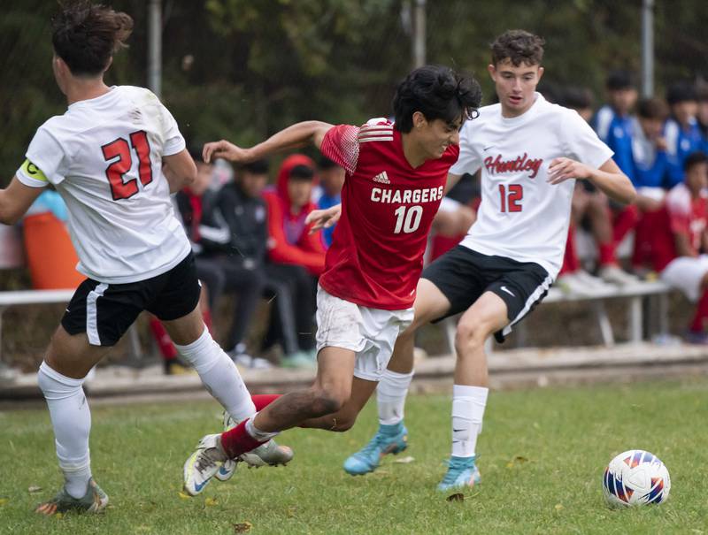 Dundee-Crown's Miguel Pena gets tripped up while battling for the ball with Huntley's Zach Heitkemper, left, and Nick Logston during their game on Thursday, October 6, 2022 at Dundee-Crown High School in Carpentersville. Dundee-Crown won 1-0.