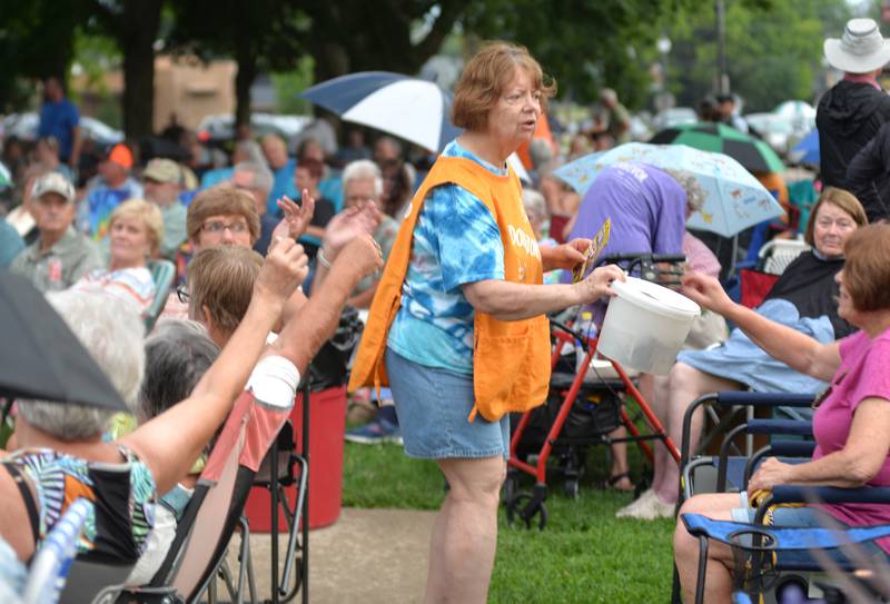 Volunteer Barn Wells makes her way through the crowd with one of the donation buckets at the Jamboree Concert Series in Mt. Morris on Friday, July 25, 2025.