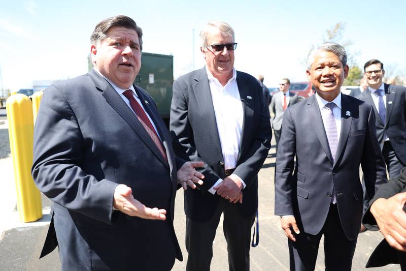 Governor J.B. Pritzker, left, speaks with John Mueller, chairman, and owner of G&W Electric, and Gil Quiniones, CEO of ComEd, at an event outside the G&W Electric building in Bolingbrook.
