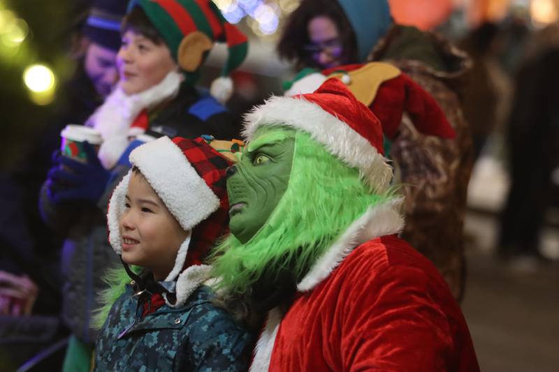 The Grinch poses with youngsters during the Festival of Lights Holiday Parade in downtown Crystal Lake on Friday, Nov. 29, 2024.