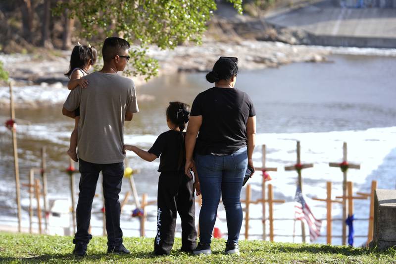 Kerrville residents Edgar Rojas, second from left, and his wife Perla, alongside daughters Emily, left, and Olivia, visit a memorial for flood victims along the Guadalupe River on Thursday, July 10, 2025, in Kerrville, Texas. (AP Photo/Gerald Herbert)