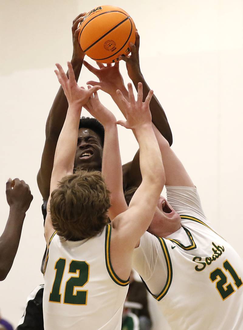 Kaneland's Jeffrey Hassan grabs a rebound over Crystal Lake South's Vincent Santarelli (left) and Ryan Morgan (right) during the IHSA Class 3A Rochelle Sectional championship basketball game on Friday, March 7, 2025, at Rochelle High School.