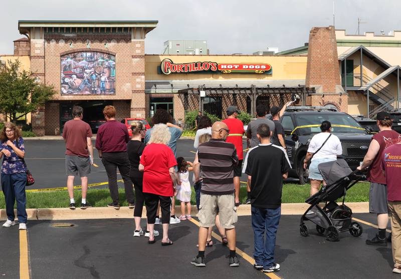 A crowd of onlookers gathered Wednesday, July 30, 2025, at the scene where a car crashed through the front entrance of the Portillo’s at 2810 U.S. Route 34 in Oswego injuring 12.