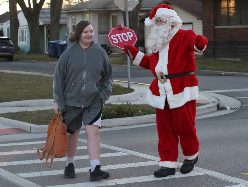 Santa Claus helps Grant Mead walk across St. Vincent Avenue on Wednesday, Dec. 20, 2023 at Lincoln Junior High School in La Salle. Santa came to the school to assist students as the crossing guard for the morning.