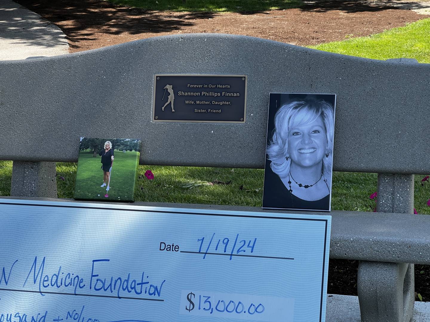 Pictures of Shannon Finnan adorn a bench in her honor, which sits outside of the first hole of the River Heights Golf Course in DeKalb, on July 19, 2024.