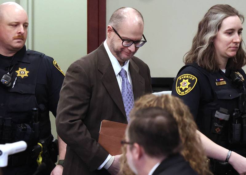 Jonathan Hurst is escorted to his seat by two DeKalb County Sheriff’s deputies Thursday, Jan. 23, 2025, during his trial at the DeKalb County Courthouse in Sycamore. Hurst is charged in the 2016 slayings of Sycamore elderly mother and son Patricia and Robert Wilson.