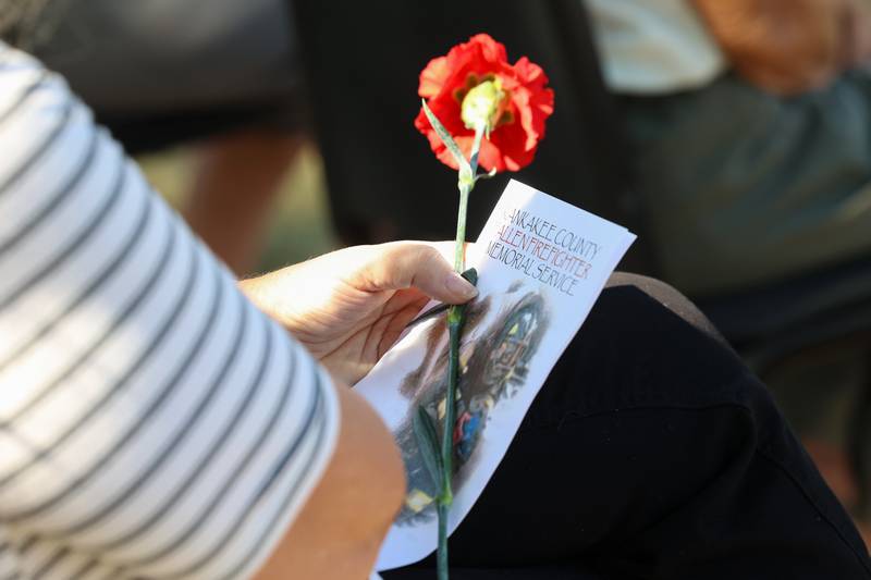 A family member holds a flower in honor of their fallen firefighter during the 44th Kankakee County Fallen Firefighter Memorial Service on Friday, Oct. 3, 2025.