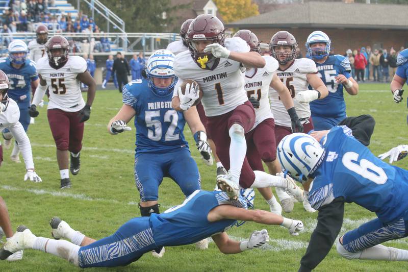 Montini Catholic's Santino Florio hurdles Princeton players Ace Christiansen and Jaydon Cooke during the Class 3A quarterfinal game on Saturday, Nov. 16, 2024 at Bryant Field in Princeton.