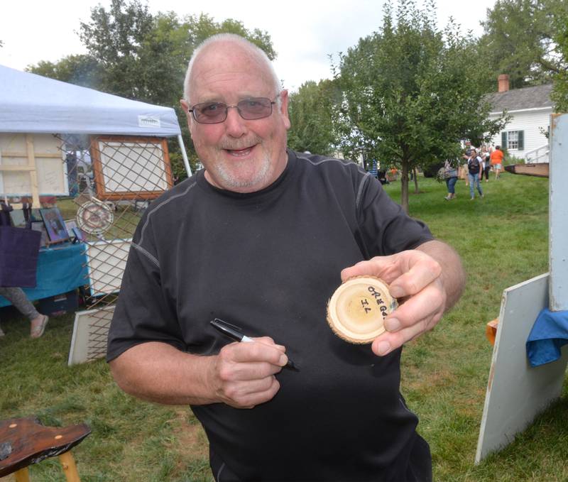 Peter Bell of Oregon hands out one of us unique business cards for his rustic wood creations at the 74th Grand Detour Arts Festival held at the John Deere Historic Site in Grand Detour on Sunday, Sept. 10, 2023.