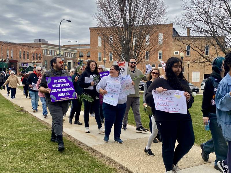 Participants hold signs during a procession at a Palm Sunday Faith Action event on Sunday, March 29, 2026, in front of the DeKalb County Courthouse in Sycamore. Area Christian ministers organized the event to combat the rise of Christian nationalism in the U.S.