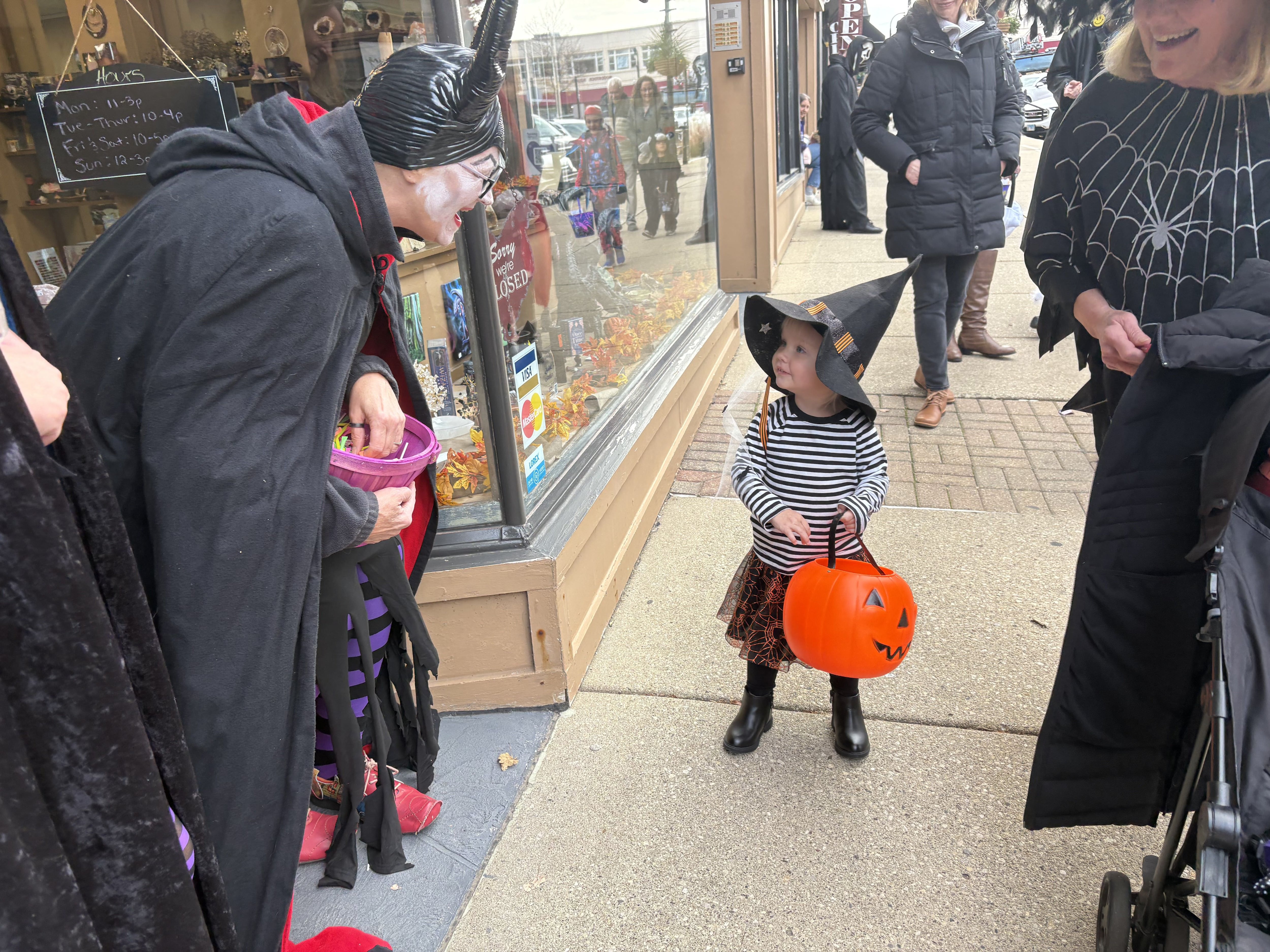 Kira Forner, 2, of Chesterfield, Missouri, right, gets ready to get a piece of candy from Cindy Huffman during Halloween on the Square in Woodstock Oct. 31, 2025.