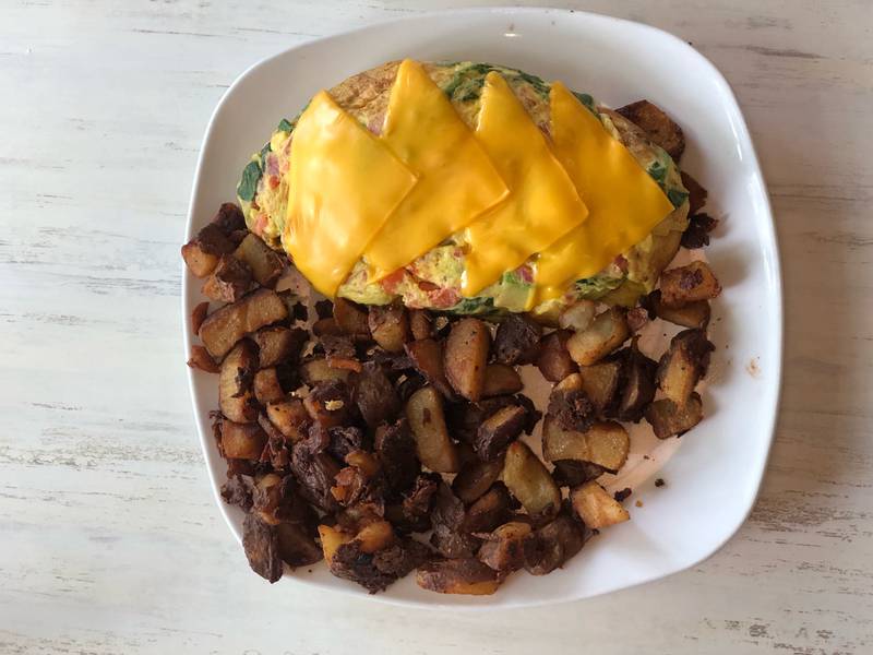 The cheesy omelet at Syrup restaurant in Algonquin is loaded with tomatoes, spinach and avocado with a side of crunchy potatoes.