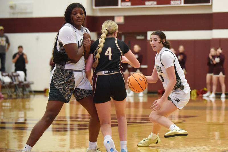 Bishop McNamara's Trinity Davis, right, looks for a lane to the basket as teammate Leigha Brown, left, sets a screen on Mt. Carmel's Riley Hershey during the IHSA Class 2A Tolono Unity Super-Sectional Monday, March 3, 2025.
