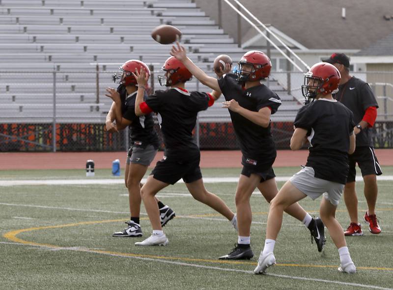 Huntley quarterbacks throw the football team during the first day of football practice Monday, August 7, 2023, at the Huntley High School’s Red Raider Stadium.
