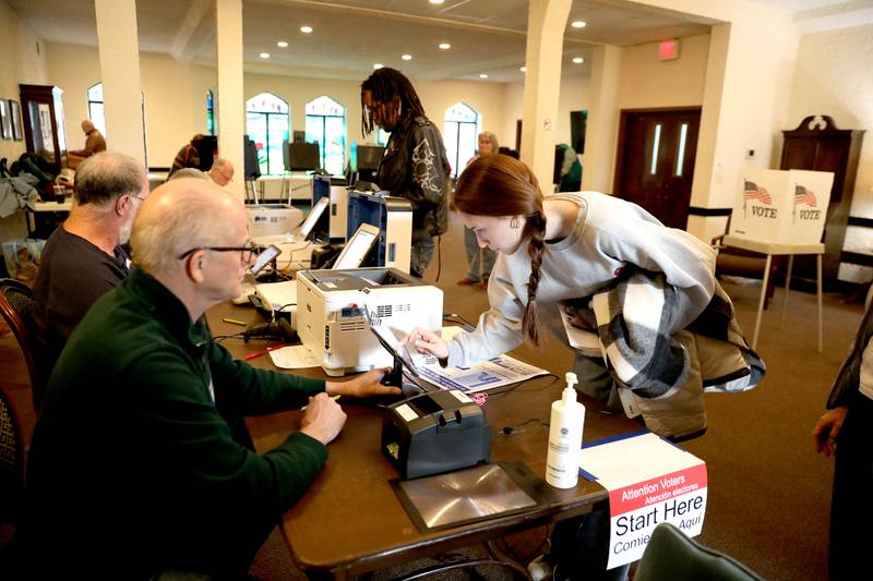 Election Judge Neil Coleman (left) helps voter Audrey Lee at the First Methodist Church polling place in Downers Grove for the General Election on Tuesday, Nov. 8, 2022.